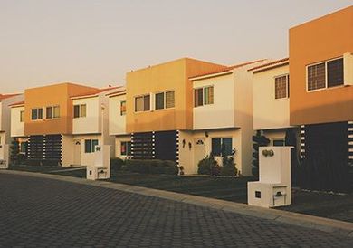 Rangée de maisons de ville modernes beiges avec des touches d'orange le long d'une allée pavée au coucher du soleil
