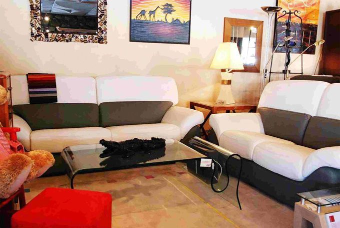 Deux canapés blanc et gris devant une table basse en verre dans une pièce.