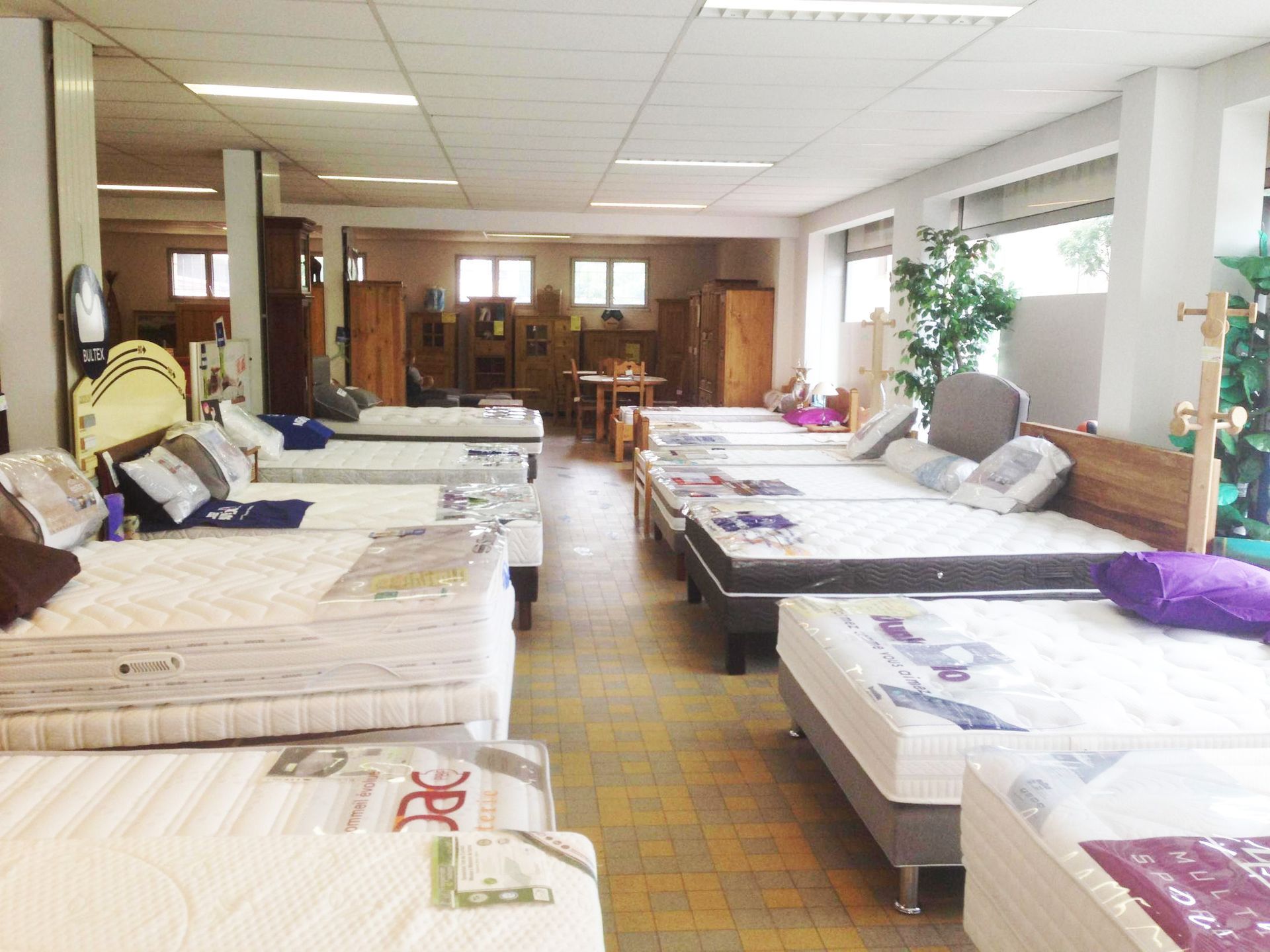 Une exposition de plusieurs matelas sur des lits dans une grande pièce.