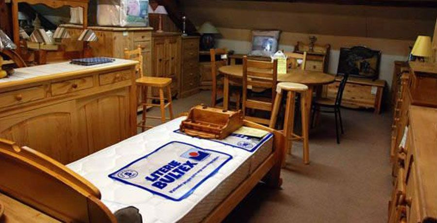 Plusieurs mobiliers en bois devant un matelas sur un lit.