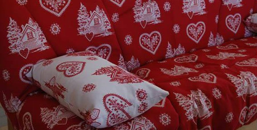 Gros plan sur le coussin d'un canapé rouge à motifs blanc.