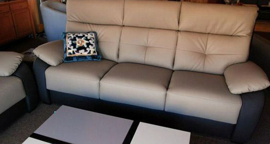 Un canapé en simili cuir couleur crème et gris devant une table basse.