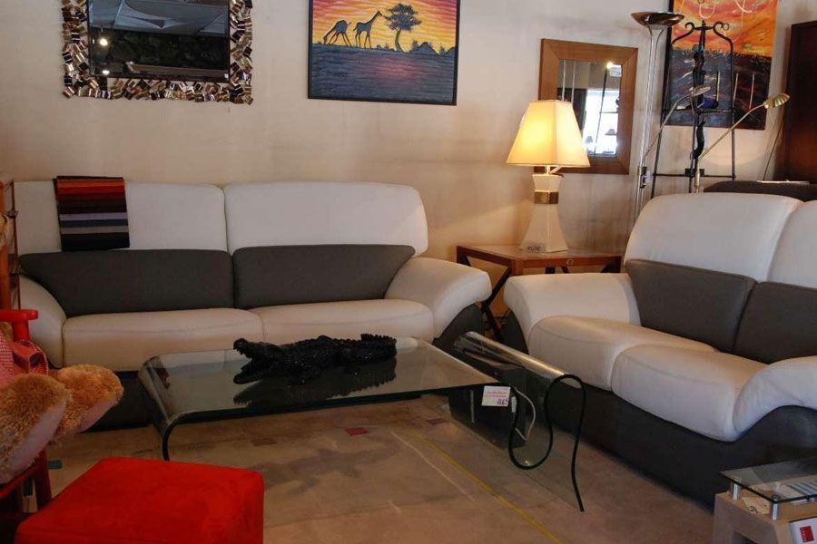 Deux canapés blanc et gris autour d'une table basse en verre dans un salon.