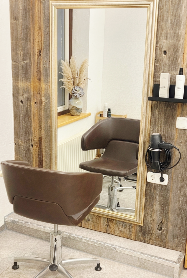 Ein Spa-Behandlungsraum mit einem mit Handtüchern bedeckten Liegestuhl, einer Buddha-Statue und einem Schönheitsposter an der Wand.