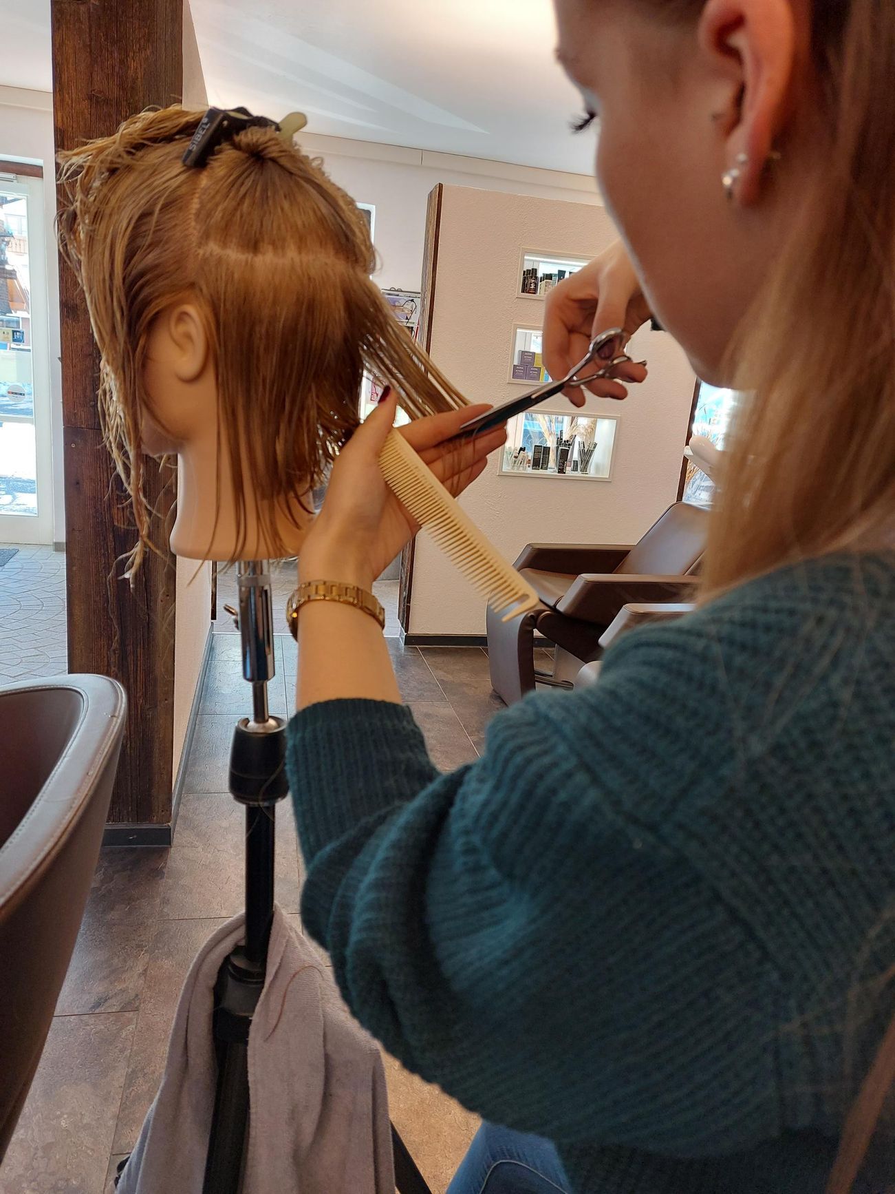 Eine Friseurin stylt in einem Salon die Haare einer Kundin mit einem Lockenstab.