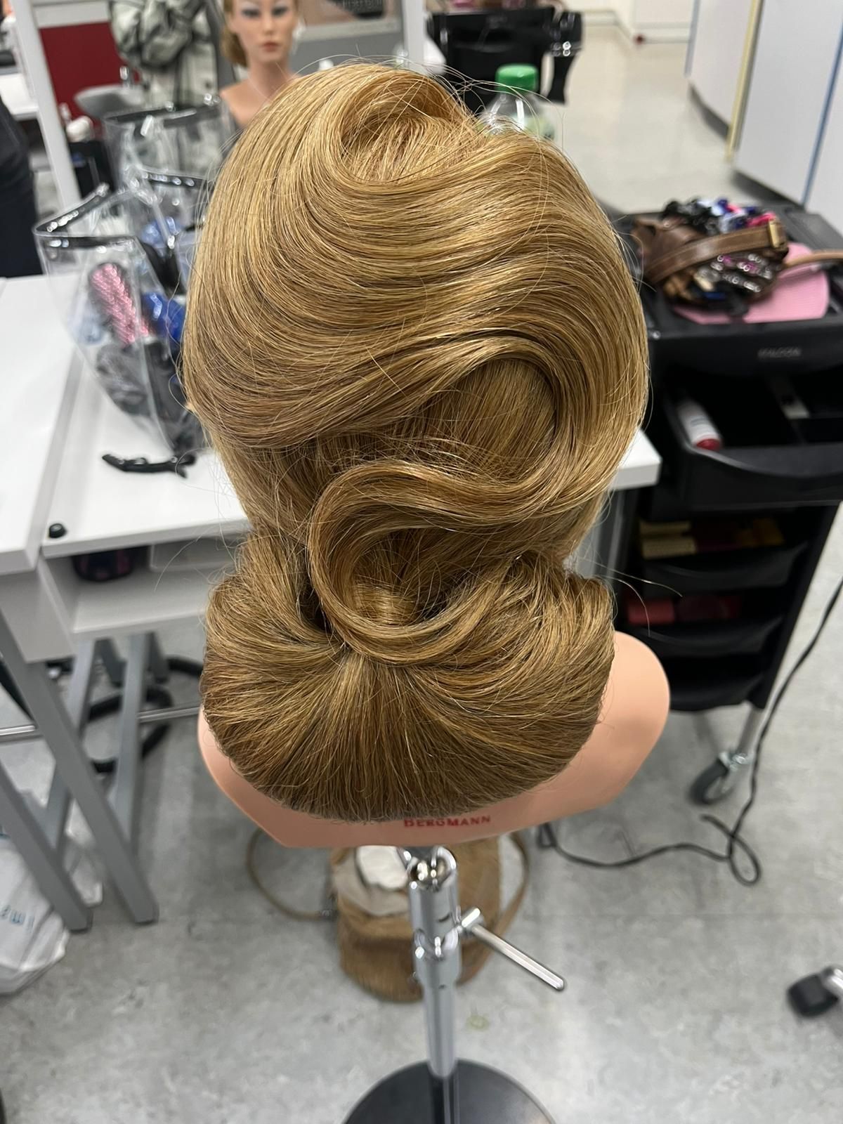 Eine Person in schwarzer Jacke, die einen Strauß weißer Rosen hält; im verschwommenen Hintergrund ist eine weitere Person zu erkennen.