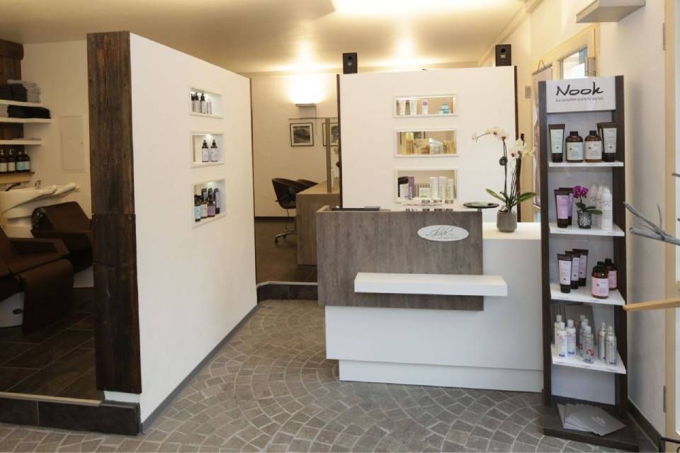 Ein modernes Saloninterieur mit Rezeption, Produktpräsentationsregalen und einem Wartebereich mit Waschplätzen.