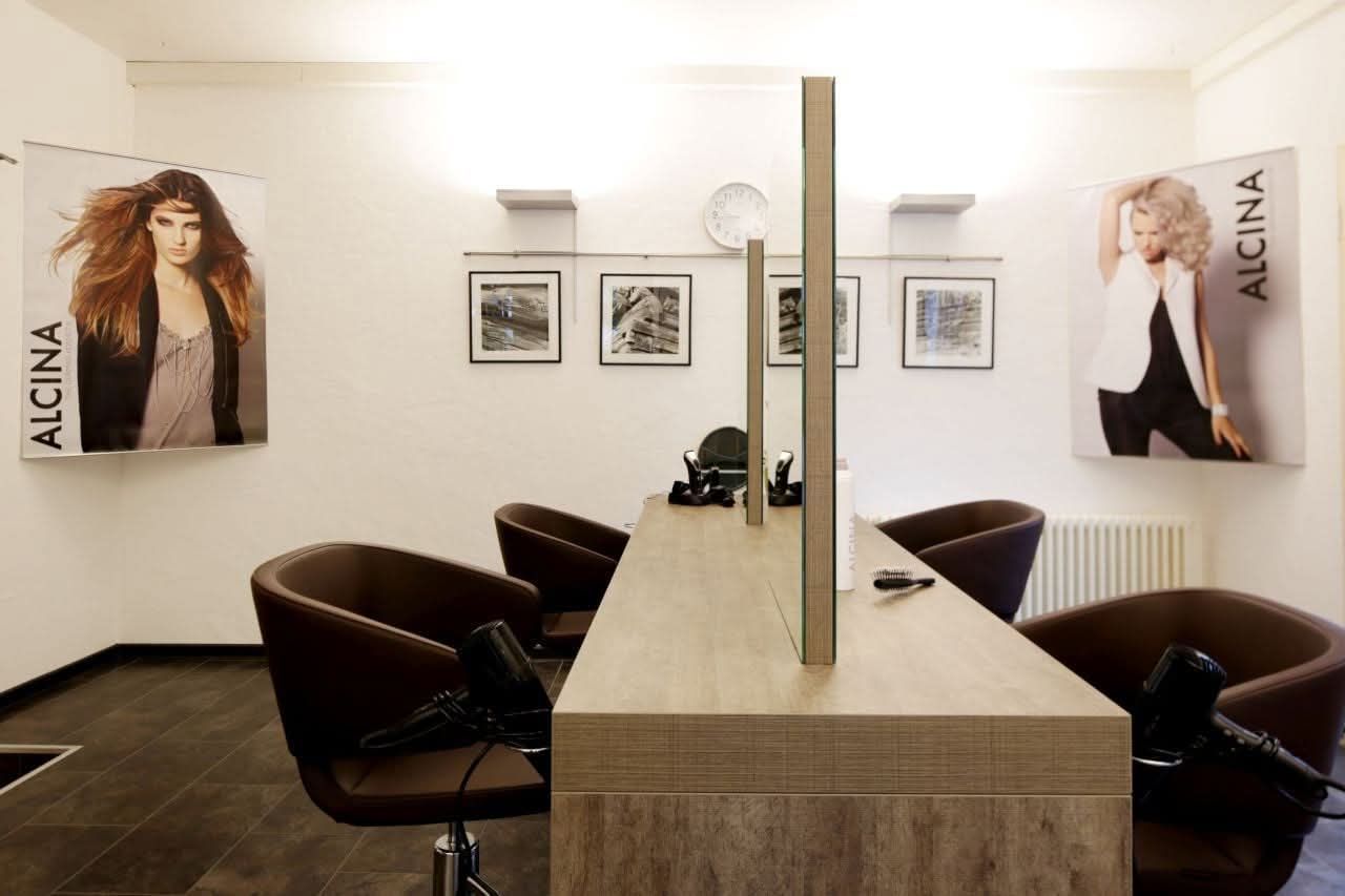 Modernes Saloninterieur mit Friseurstühlen, Spiegeln und Wandpostern in einem hellen Raum