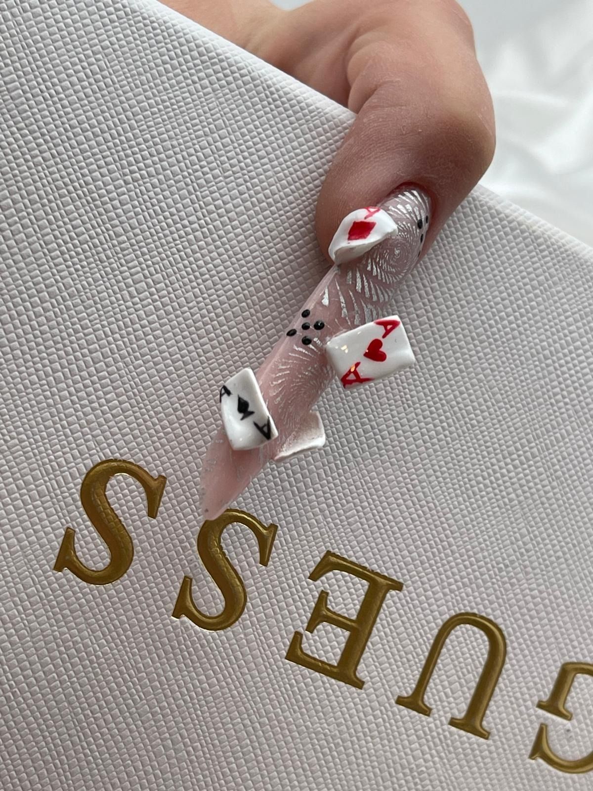 Una uña larga y bien cuidada, decorada con miniaturas de cartas de póker en 3D