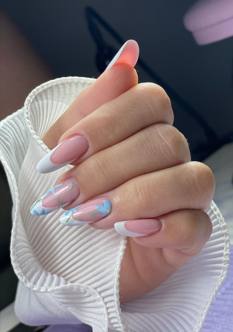 Uñas con forma de almendra que combinan la clásica punta francesa blanca con diseños de puntas en azul claro