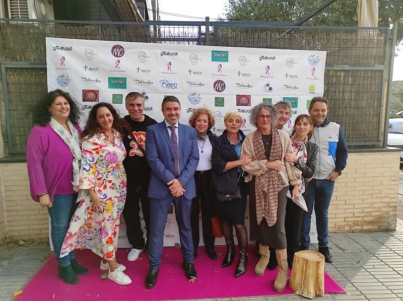 Un grupo de personas posa para una foto frente a una pared con logotipos.