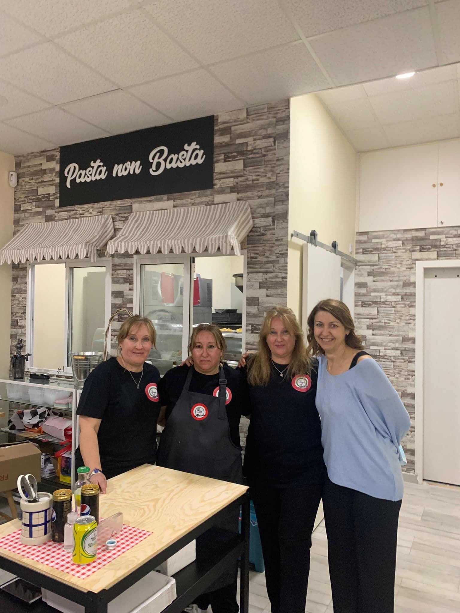 Tres mujeres posan para una foto frente a un cartel que dice pasta non basta