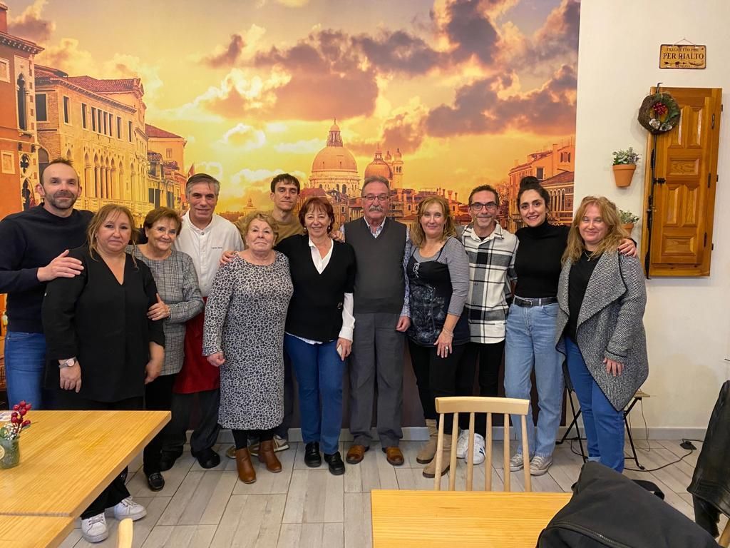 Un grupo de personas posando para una foto frente a una pared con una imagen de Venecia.