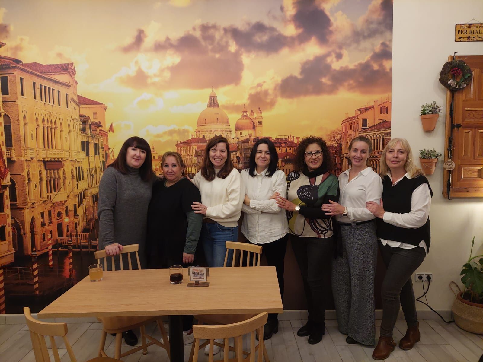 Un grupo de mujeres posa para una foto frente a un cuadro de Venecia.