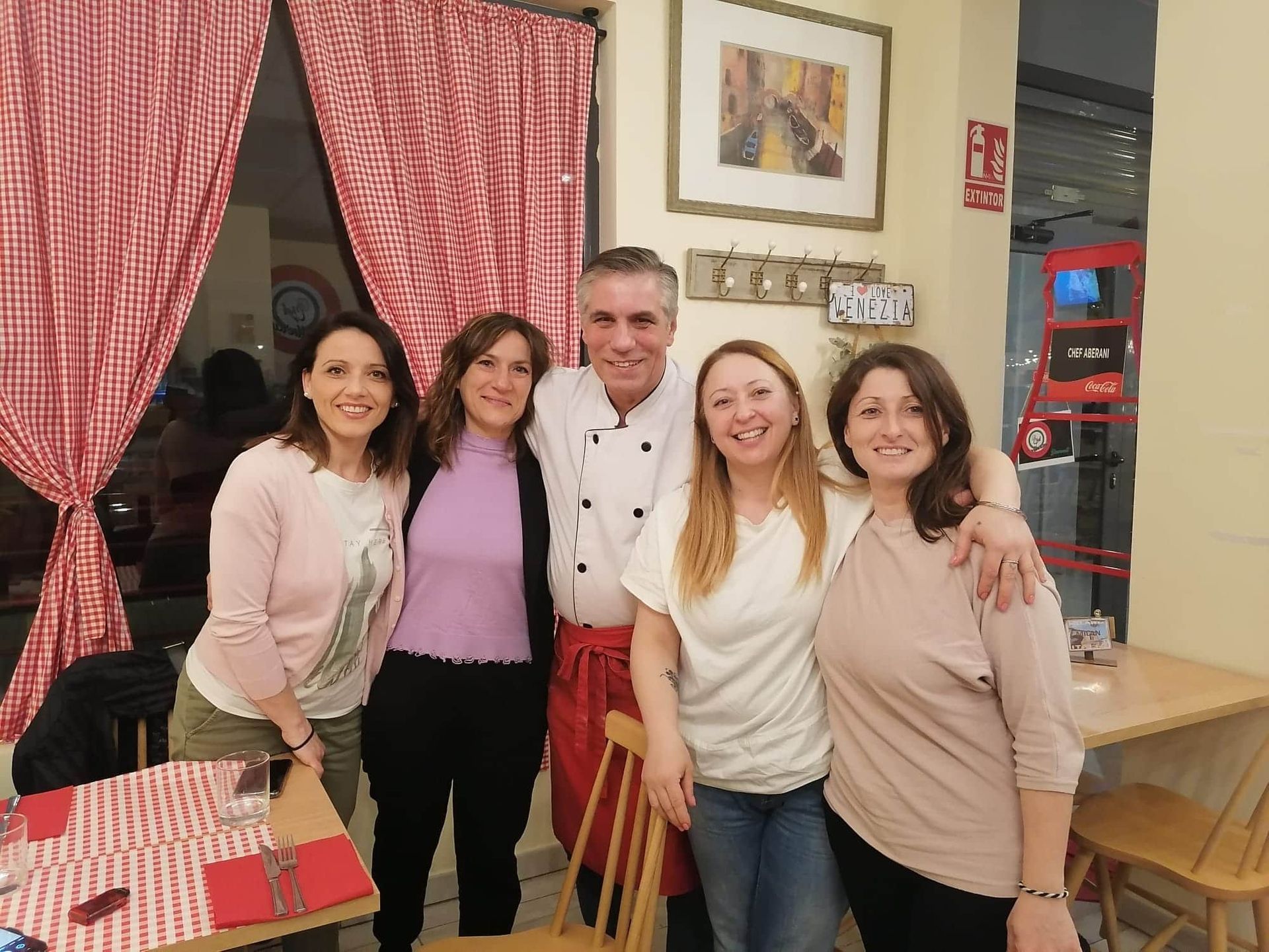Un grupo de personas posando para una foto frente a un cartel que dice bistec.