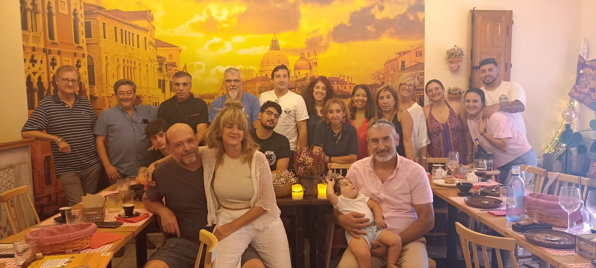 Un hombre con delantal sostiene dos papeles delante de una imagen de Venecia.