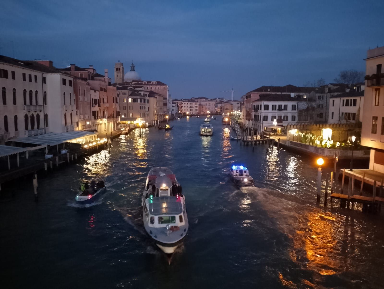 Varios barcos flotan río abajo por la noche.