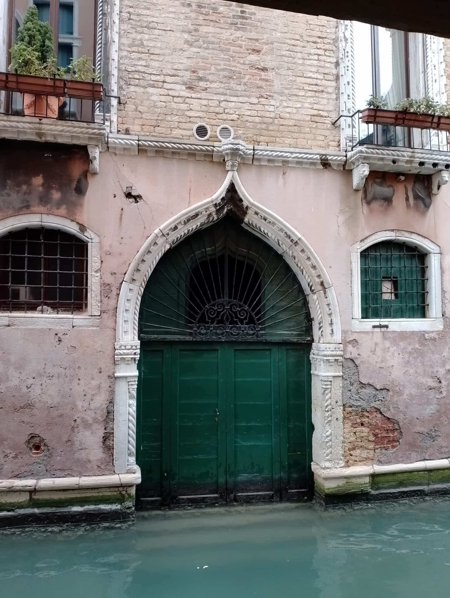 Una puerta verde está frente a un edificio rosa.