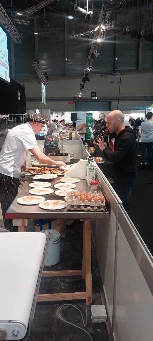 Un hombre está de pie frente a una mesa con platos de comida sobre ella.