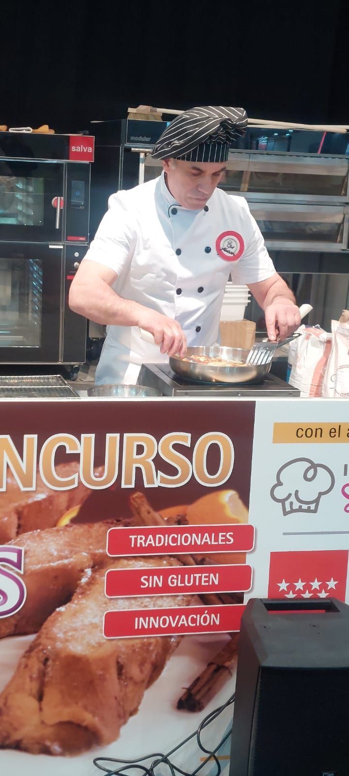 Un chef prepara comida frente a un cartel que dice concurso.