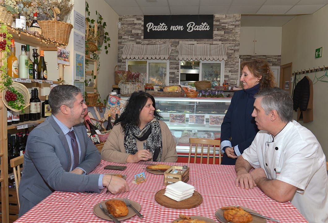 Un grupo de personas está sentado en una mesa frente a un cartel que dice pesto non basta