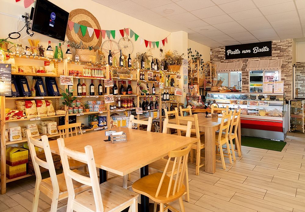 Un restaurante con mesas y sillas y un cartel que dice pasta.