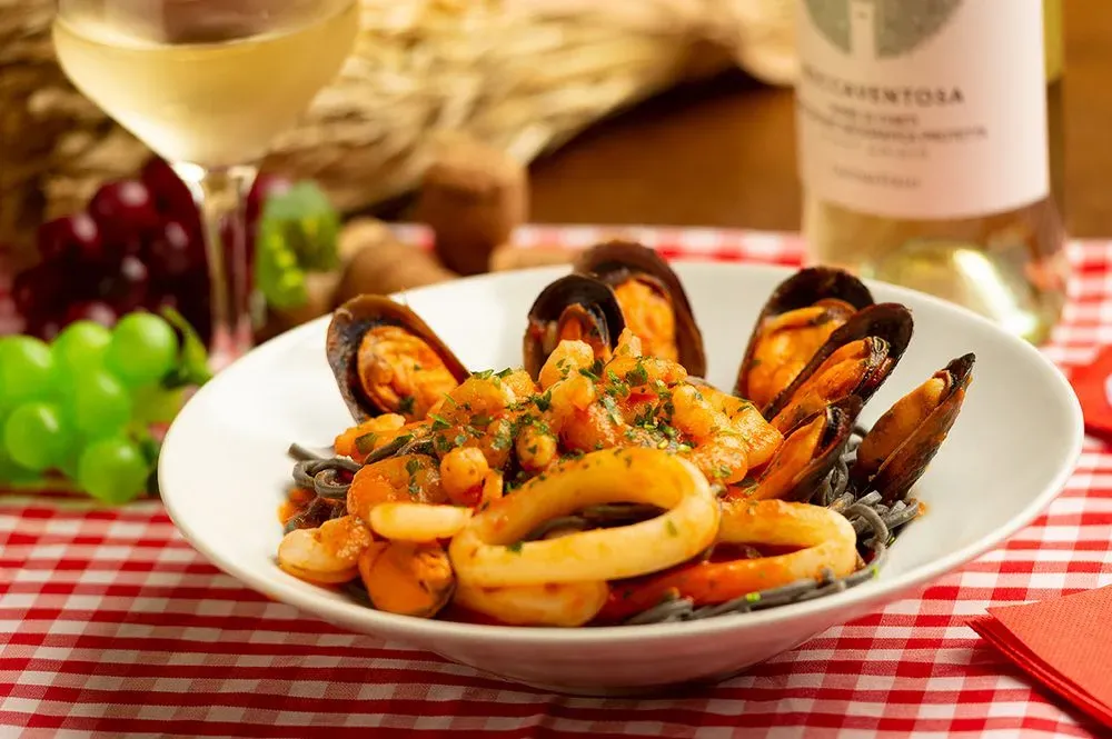 Un plato de comida con una botella de vino al fondo.