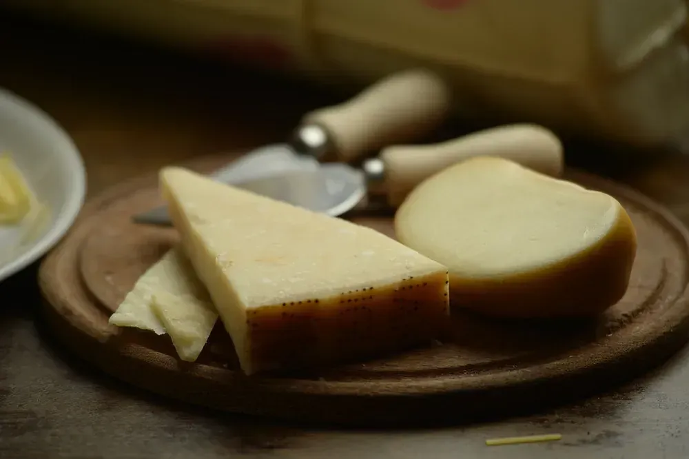 Rebanadas de queso están en una tabla de cortar de madera