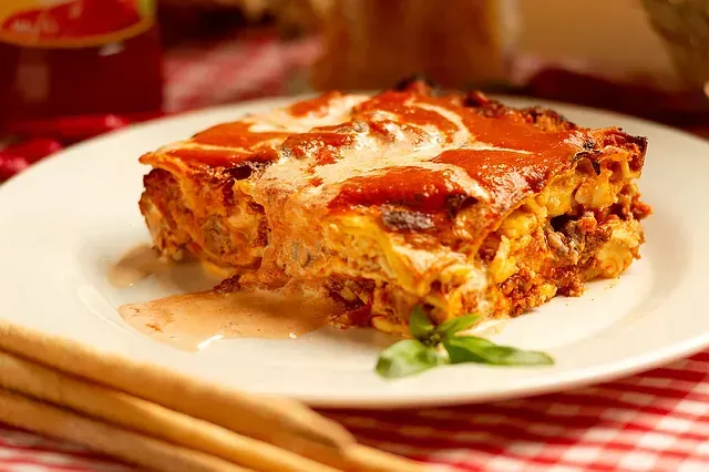 Un plato blanco cubierto con una rebanada de lasaña