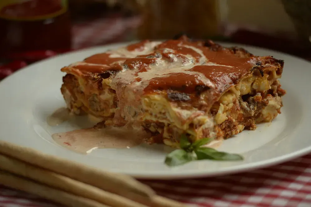 Un plato blanco cubierto con una rebanada de lasaña