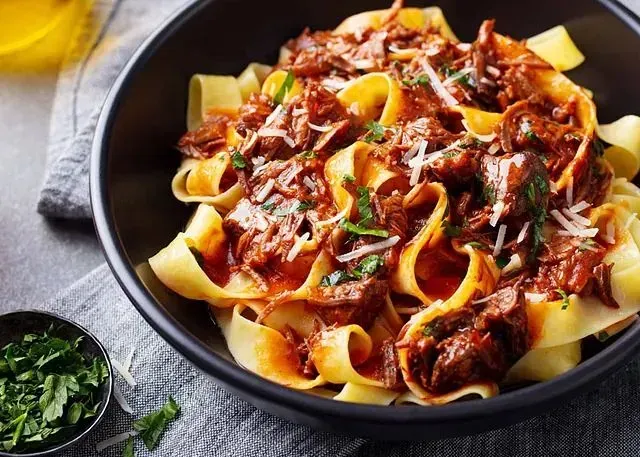 Un plato de pasta con carne y salsa sobre una mesa.