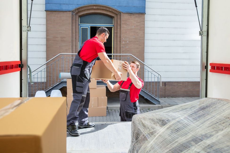 Dos hombres están cargando cajas en un camión de mudanzas.