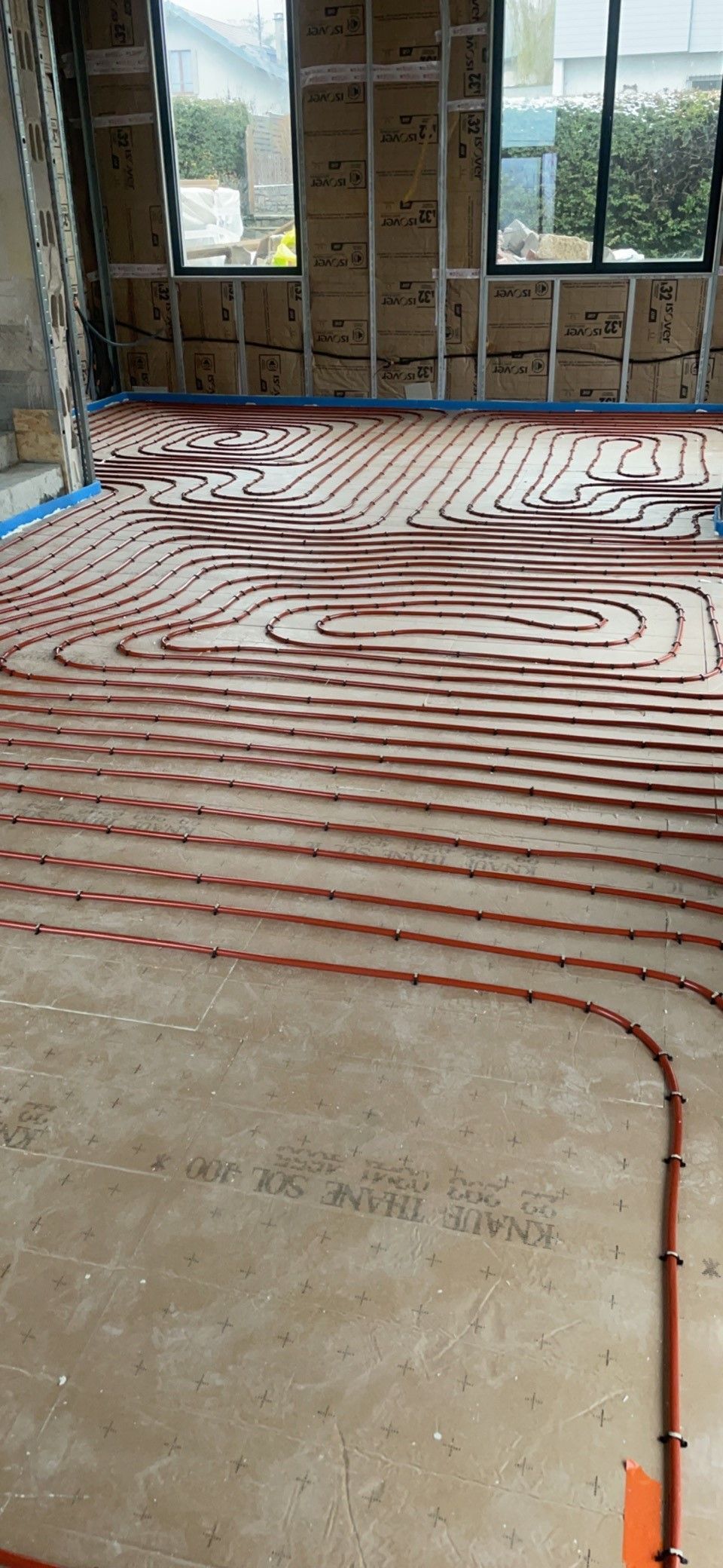 Pose d'un revêtement de sol à motifs dans une pièce avec de grandes fenêtres et des murs apparents.