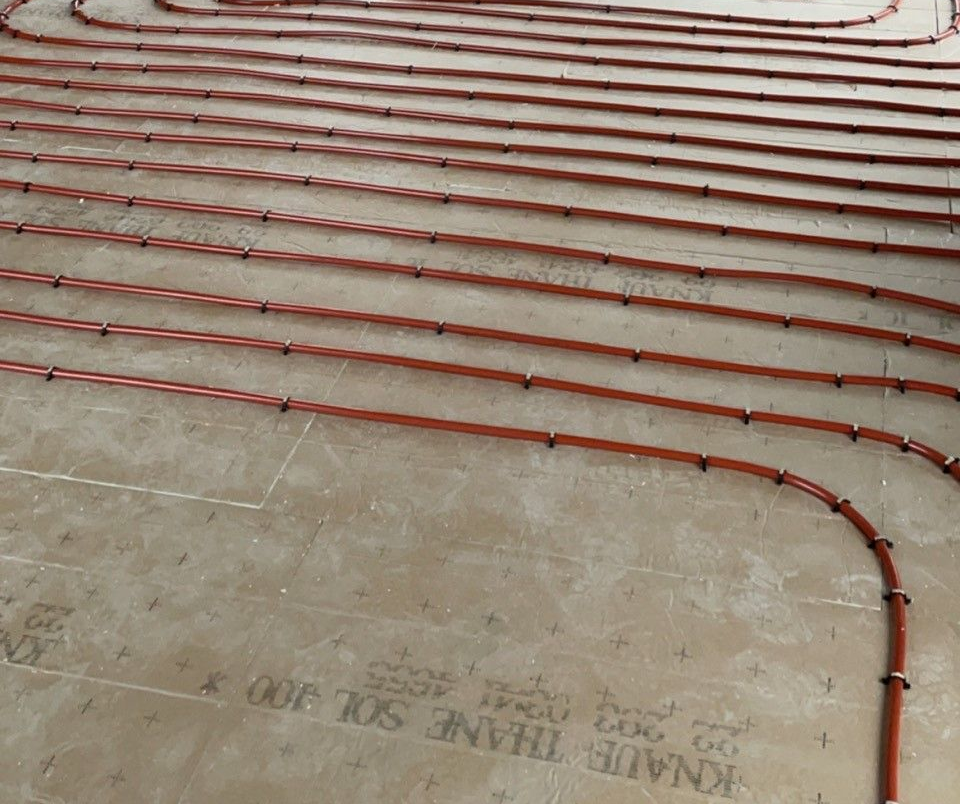 Tuyaux de chauffage au sol radiant installés dans une pièce en construction.