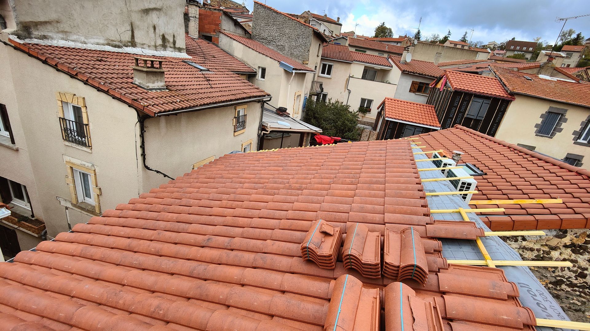 Vue d'une toiture inachevée avec des piles de tuiles neuves