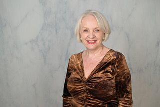 Eine Frau in einem grünen Kleid steht in einem Raum und lächelt.