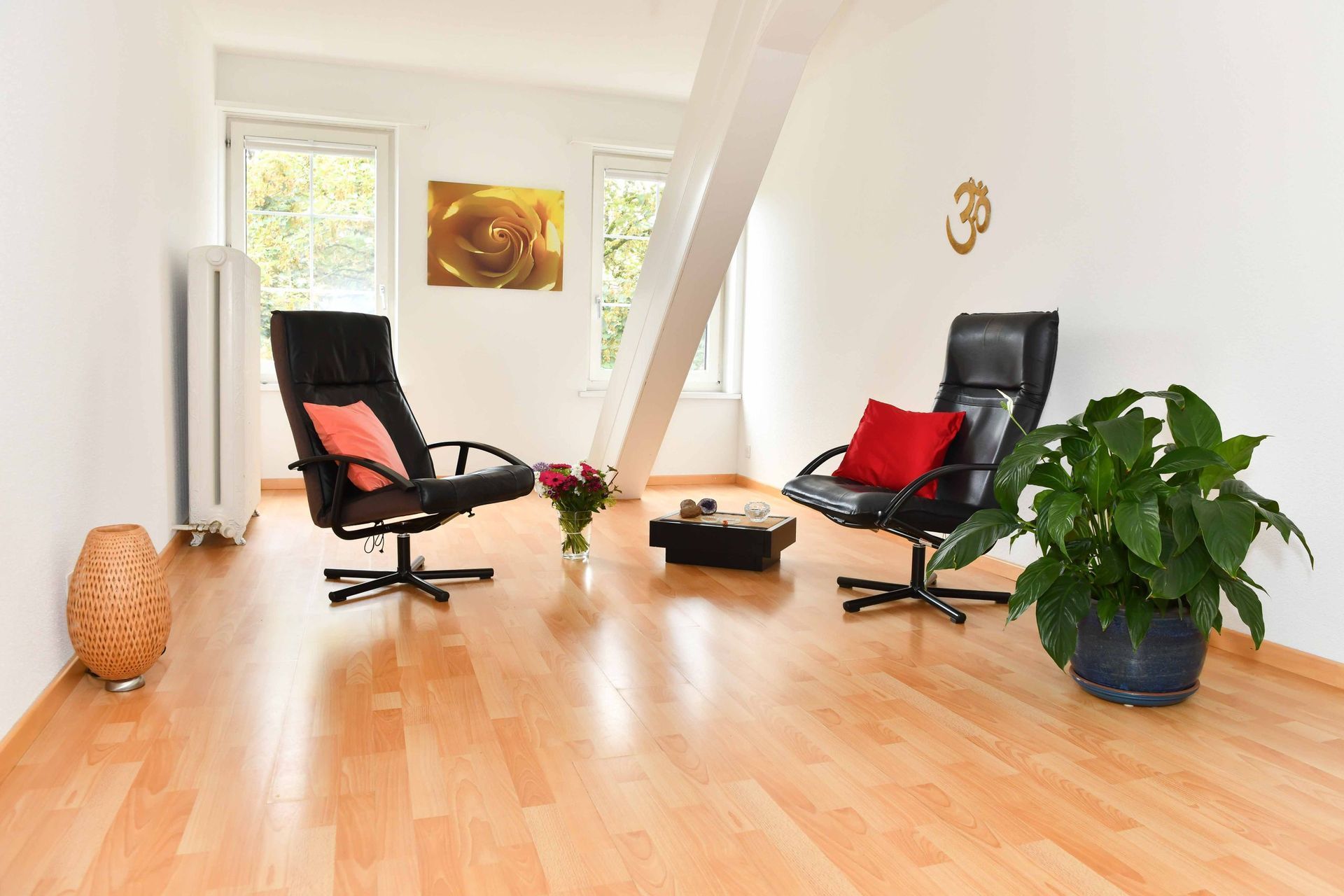 Ein Wohnzimmer mit zwei Stühlen und einer Pflanze auf dem Boden.