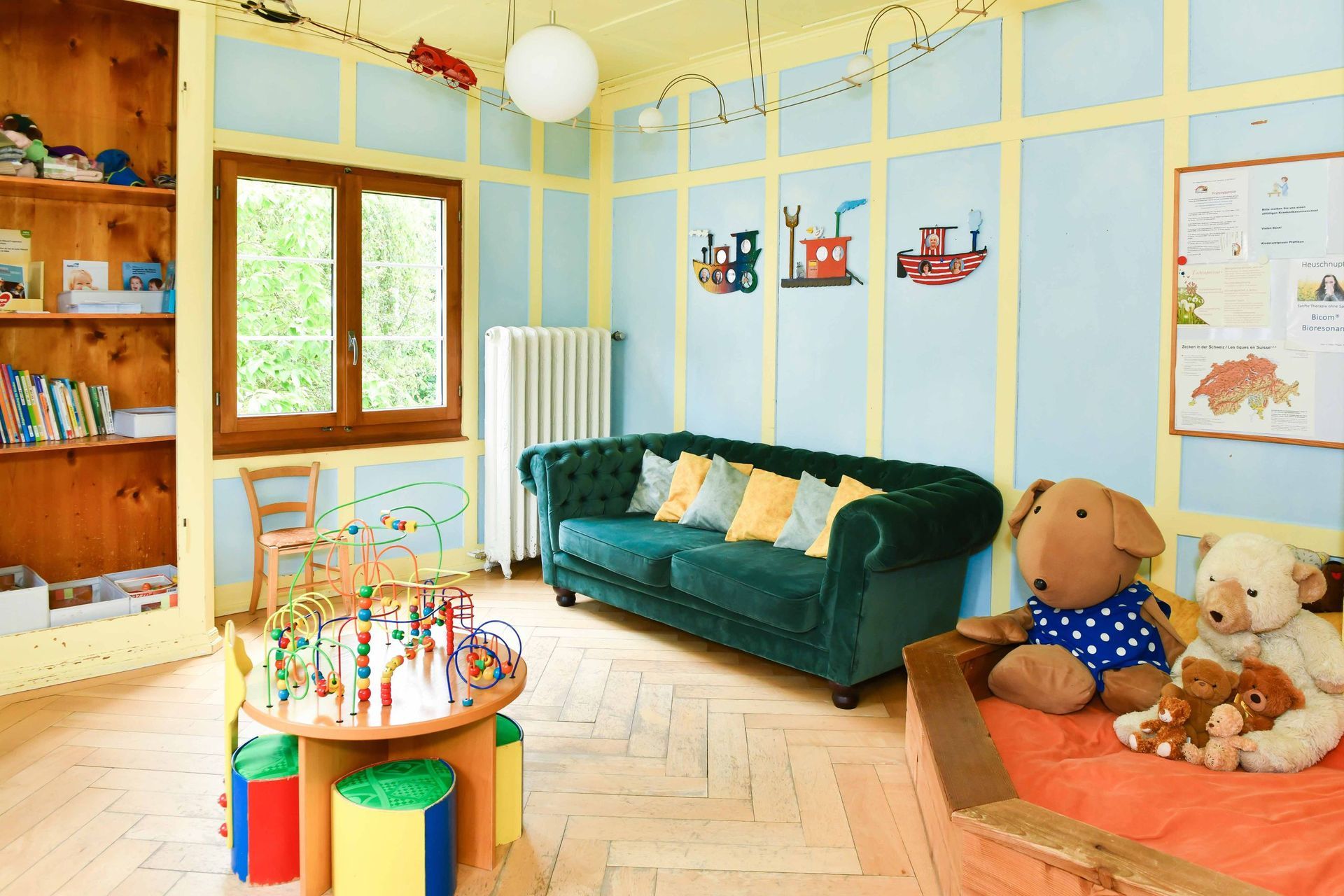 Ein Kinderzimmer mit Couch, Tisch und Teddybären.