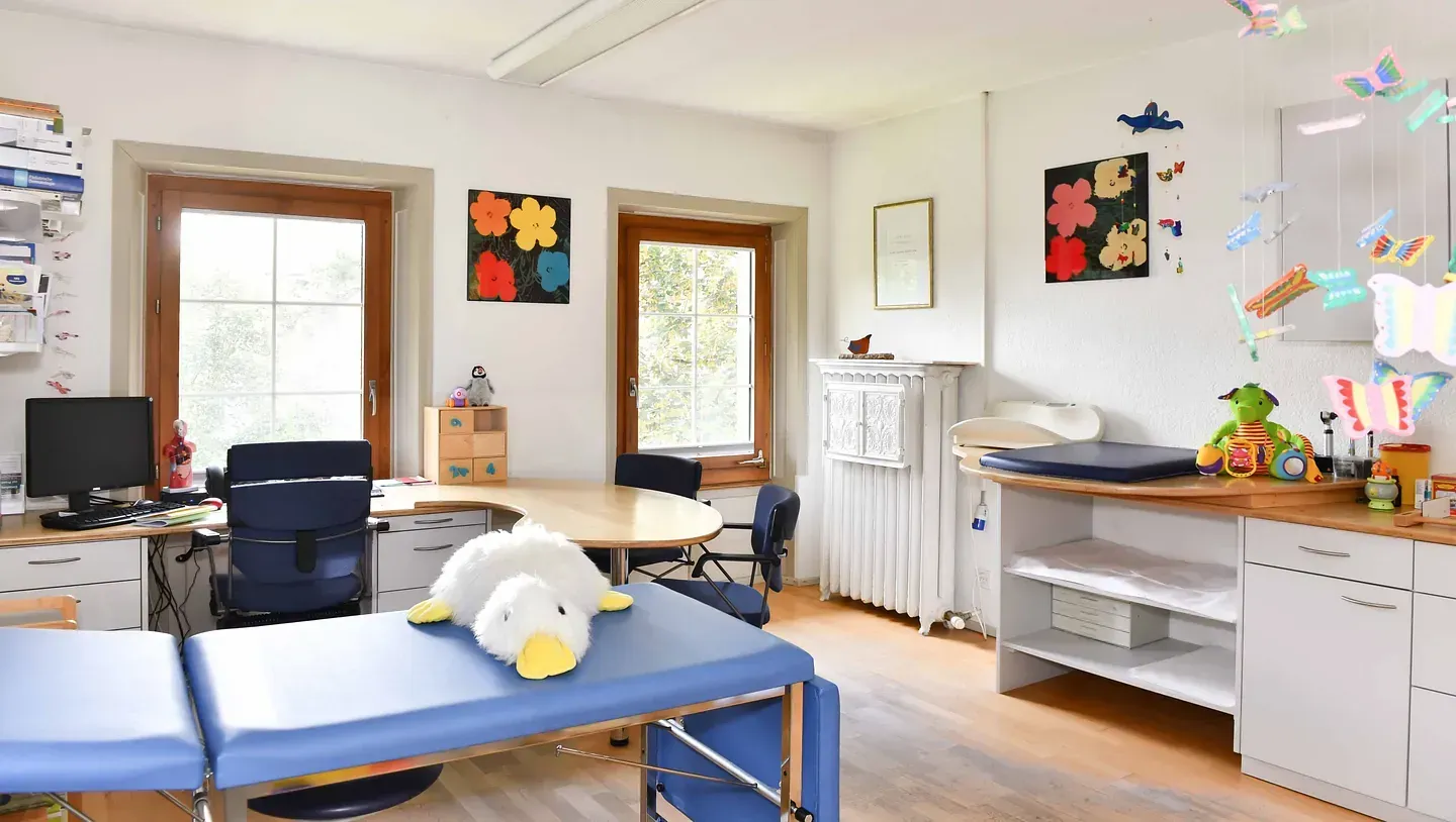 Eine Arztpraxis mit einem blauen Tisch und einem Stofftier darauf.