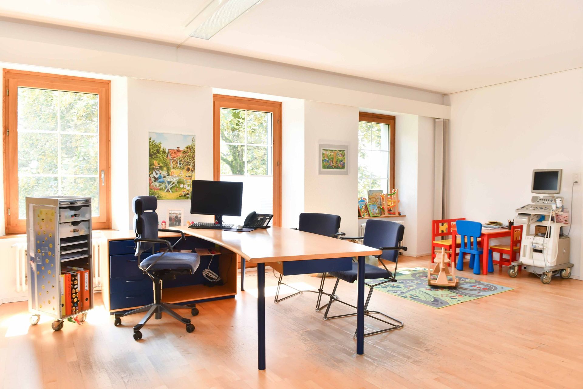 Ein Raum mit einem Schreibtisch, Stühlen und einem Computer.