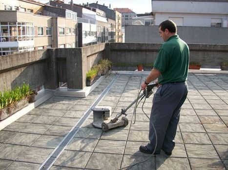 Un hombre con una camisa verde está usando una máquina para limpiar un piso de baldosas.