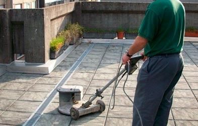 Un hombre está limpiando un piso de baldosas con una máquina.