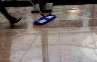 Una persona está limpiando un piso de baldosas con un trapeador.