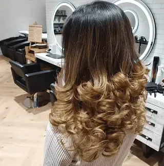Una mujer con cabello largo y rizado está sentada en una peluquería.