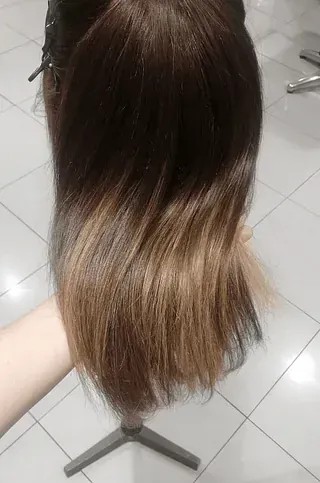 Una persona sostiene una cabeza de maniquí con cabello largo.