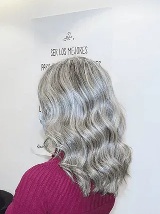 Una mujer de cabello gris lleva un suéter rosa.