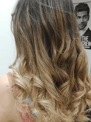 Una mujer con cabello largo y ondulado está parada frente a un hombre con traje.