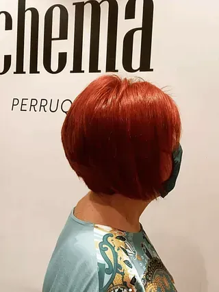 Una mujer con cabello rojo lleva una máscara y una camisa azul.