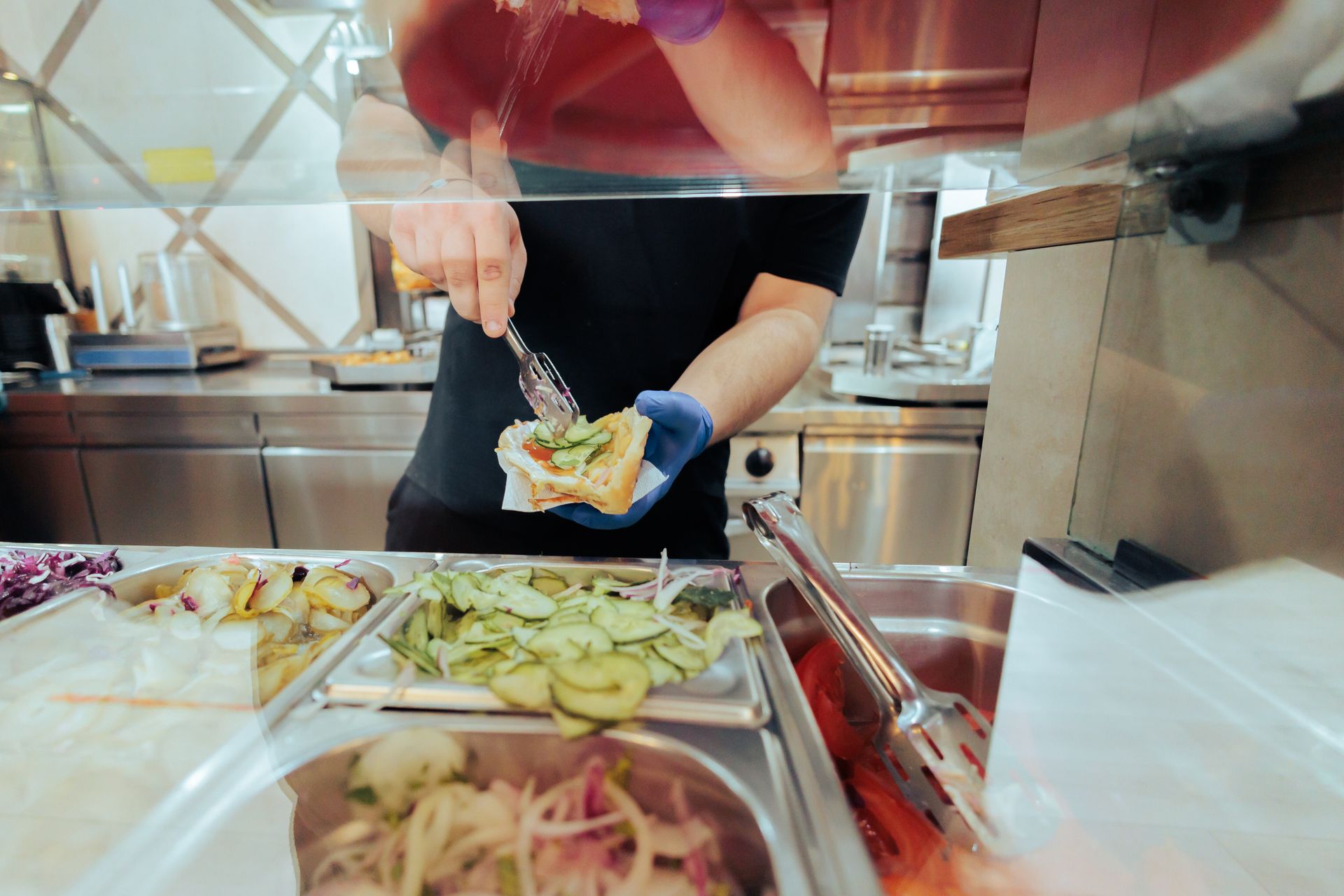 Un serveur qui ajoute des légumes dans un sandwich