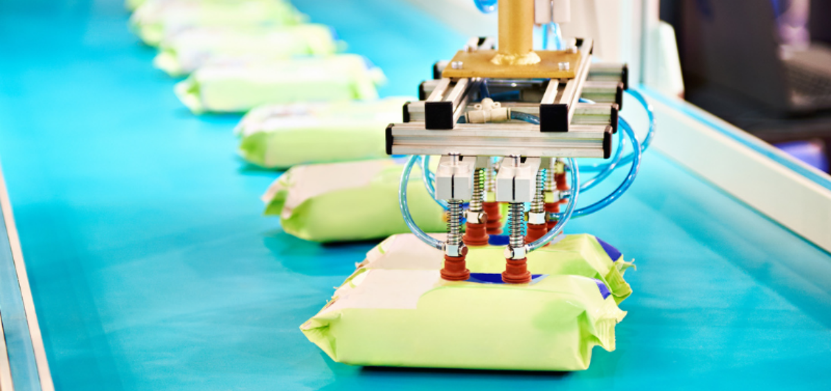 Un brazo robótico recoge un paquete en una cinta transportadora en una fábrica.